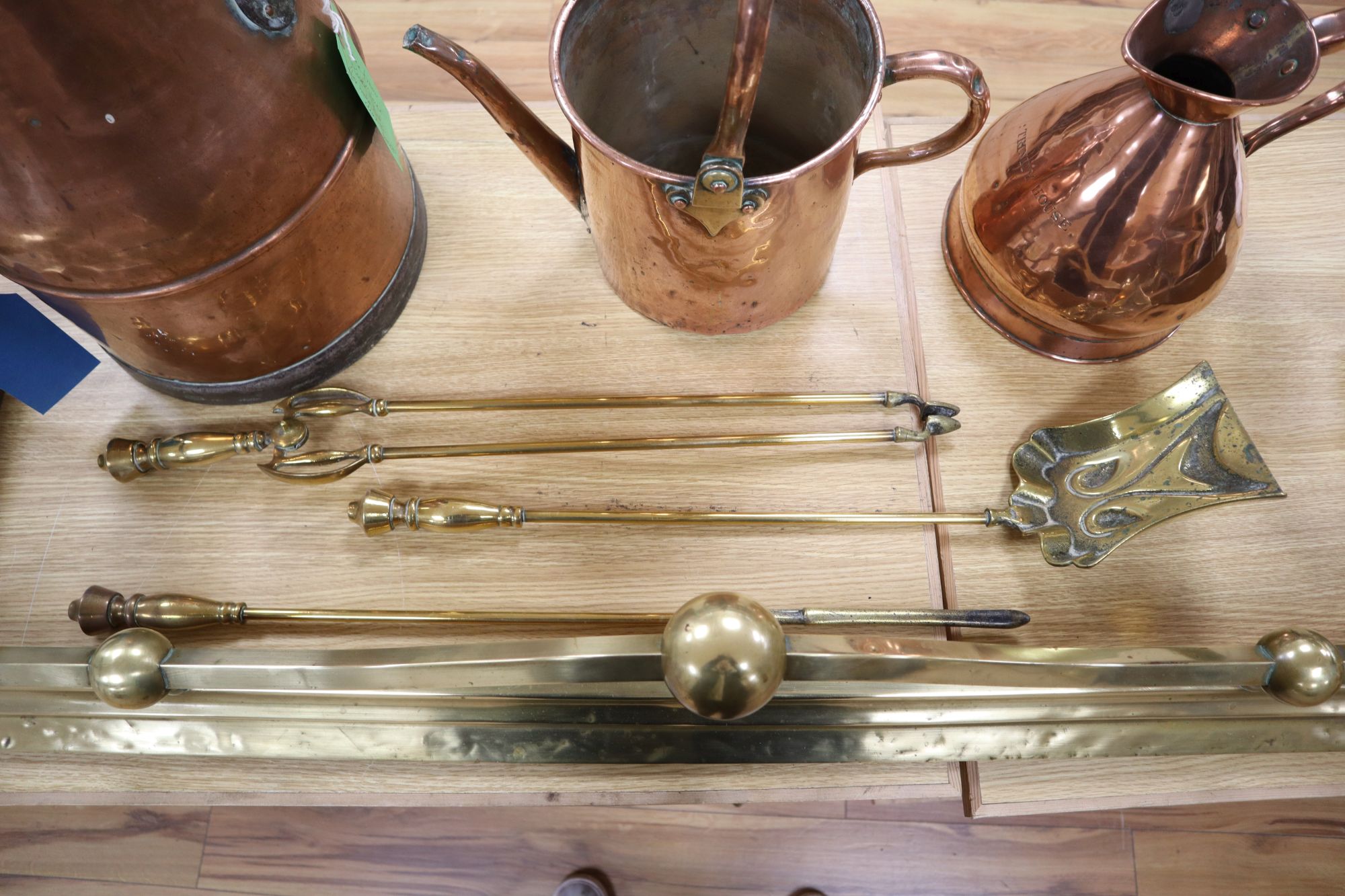 A late Victorian Art Nouveau brass fire kerb, length 132cm, a set of three Victorian fire brasses, a Dutch copper water can and a coppe